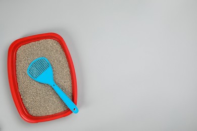 Photo of Cat litter tray with filler and scoop on light background, top view. Space for text