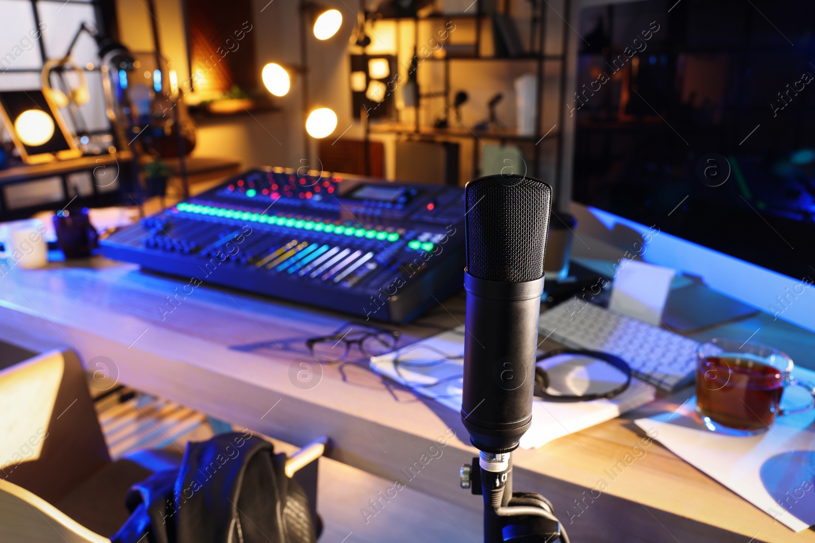 Photo of Microphone near table with professional mixing console in radio studio