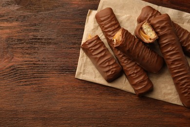 Sweet tasty chocolate bars with caramel on wooden table, top view. Space for text