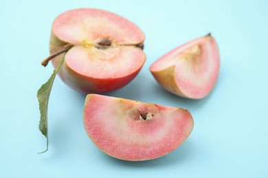 Cut apple with red pulp on light blue background, closeup