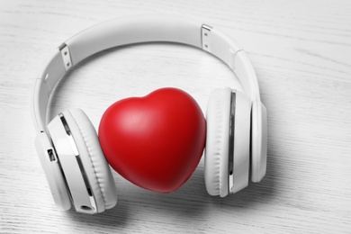 Headphones and heart on white wooden background