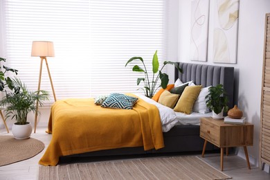 Photo of Bright plaid and colorful pillows on bed in stylish bedroom. Interior design