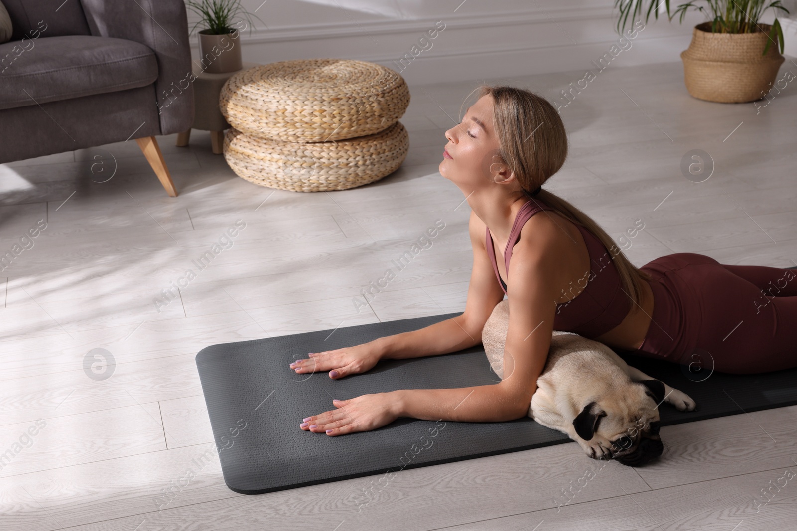 Photo of Beautiful woman with dog practicing yoga at home