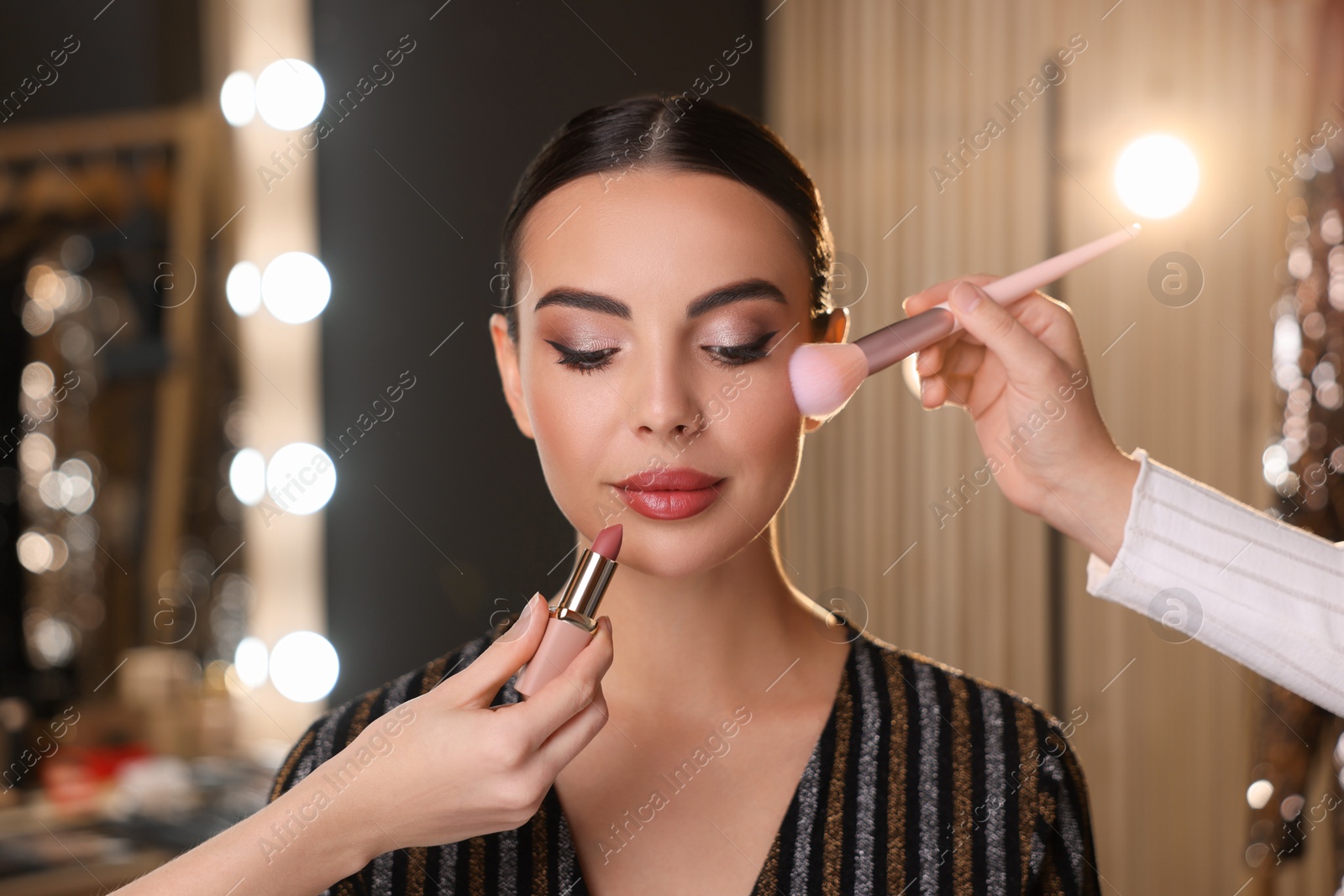 Photo of Makeup artists working with beautiful woman in dressing room