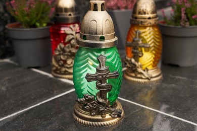 Photo of Different grave lanterns on black tiled surface outdoors