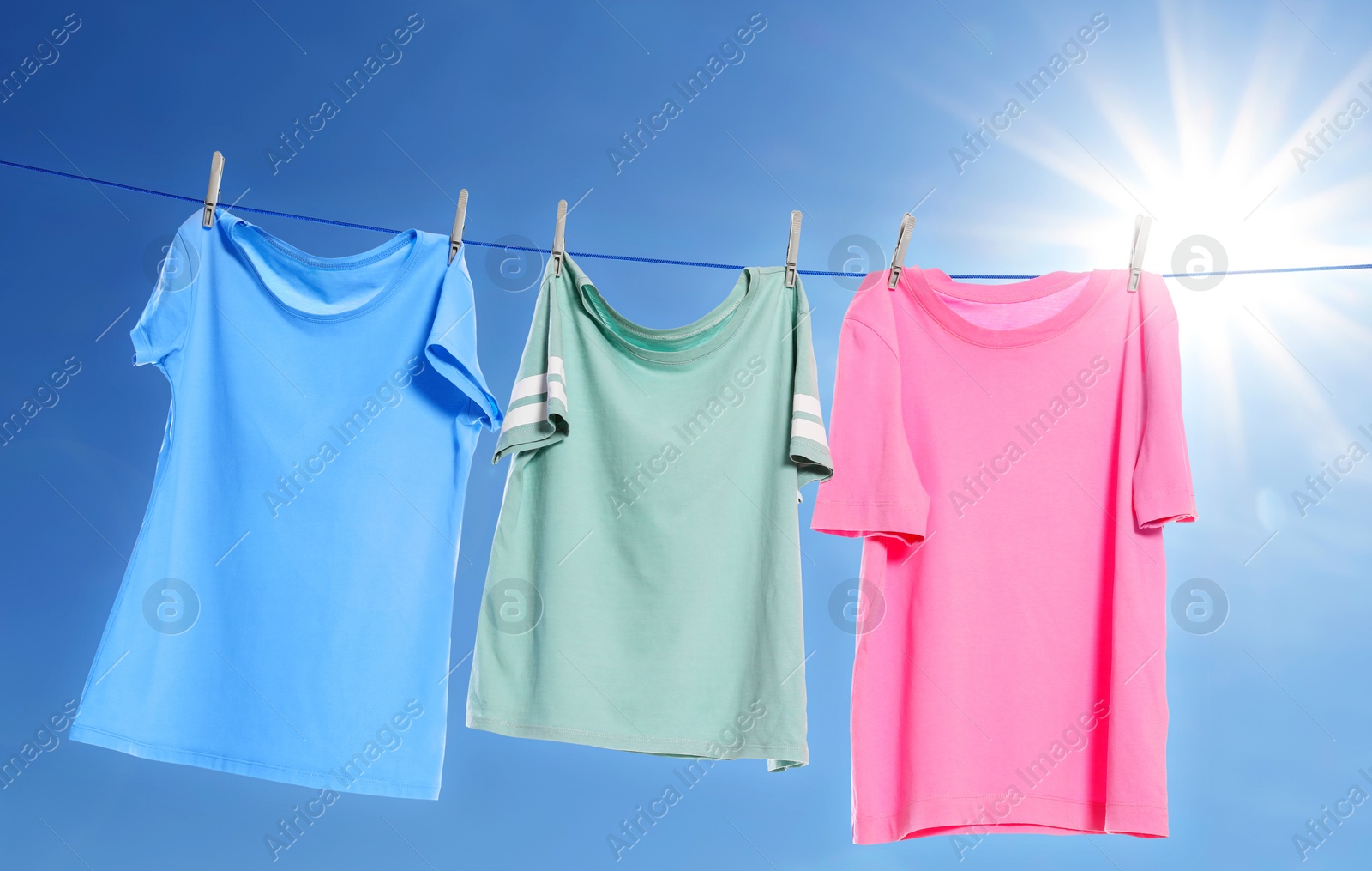 Image of Different clothes drying on washing line against blue sky