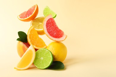 Photo of Fresh ripe citrus fruits and green leaves on beige background