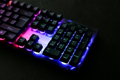 Photo of Modern keyboard with RGB lighting on black table