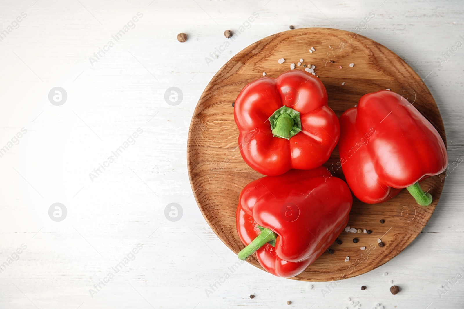 Photo of Plate with ripe paprika peppers on white wooden background, top view