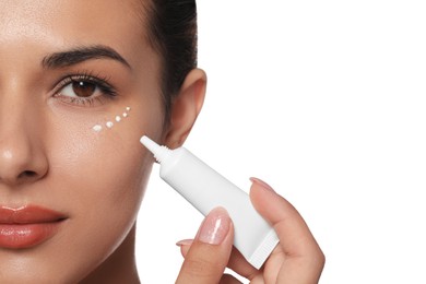 Photo of Woman applying cream under eyes on white background, closeup. Skin care