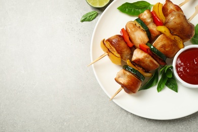 Photo of Delicious chicken shish kebabs with vegetables and ketchup on grey table, flat lay