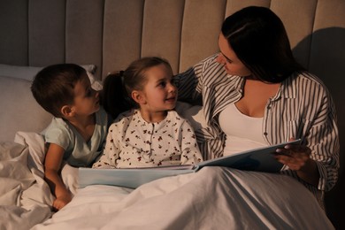 Mother reading bedtime story to her children at home