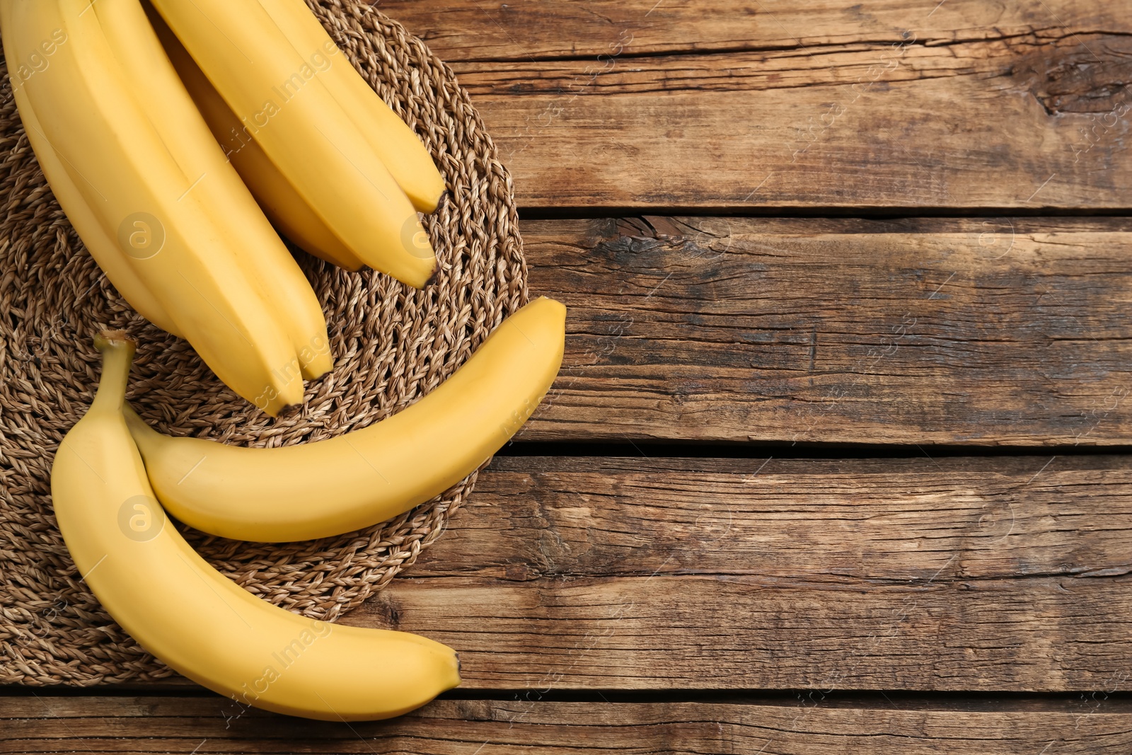 Photo of Ripe sweet yellow bananas on wooden table, flat lay. Space for text