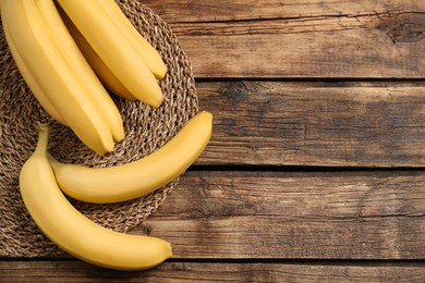 Ripe sweet yellow bananas on wooden table, flat lay. Space for text