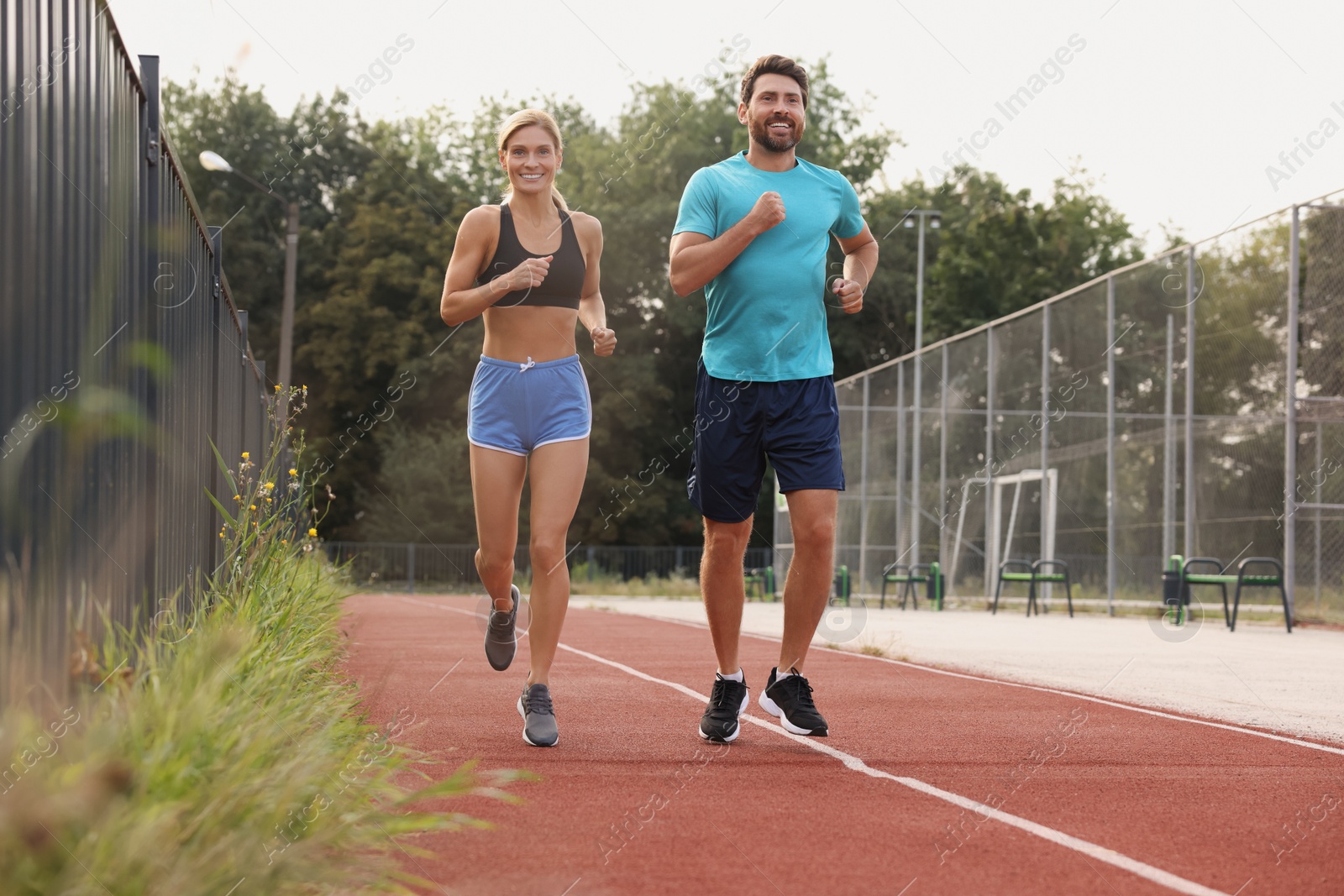 Photo of Healthy lifestyle. Happy sporty couple running at stadium