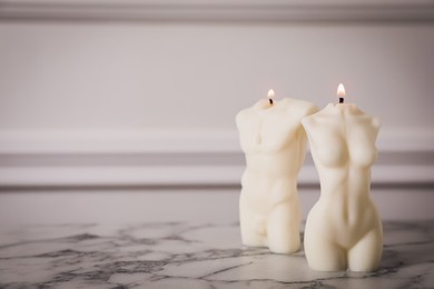 Stylish female and male body shaped candles on white marble table. Space for text