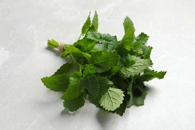 Photo of Bunch of fresh lemon balm on light gray marble table