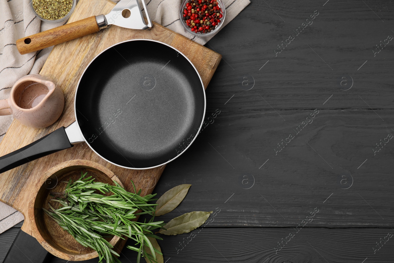 Photo of Frying pan and spices on grey wooden table, flat lay. Space for text