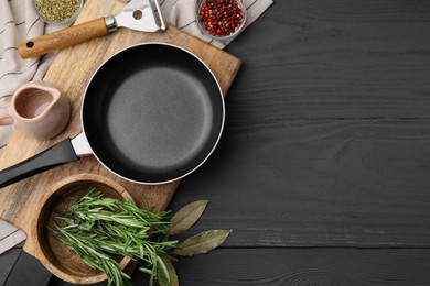 Frying pan and spices on grey wooden table, flat lay. Space for text