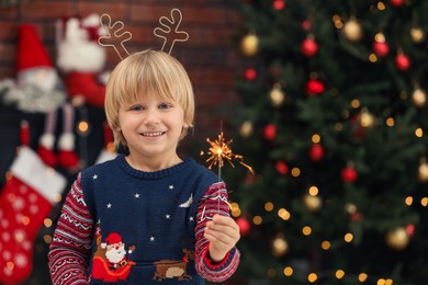 Little child with burning sparkler at home, space for text. Christmas celebration