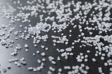 Photo of Scattered white natural salt on black table, closeup