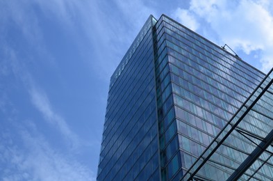 Exterior of beautiful modern skyscraper against blue sky, low angle view