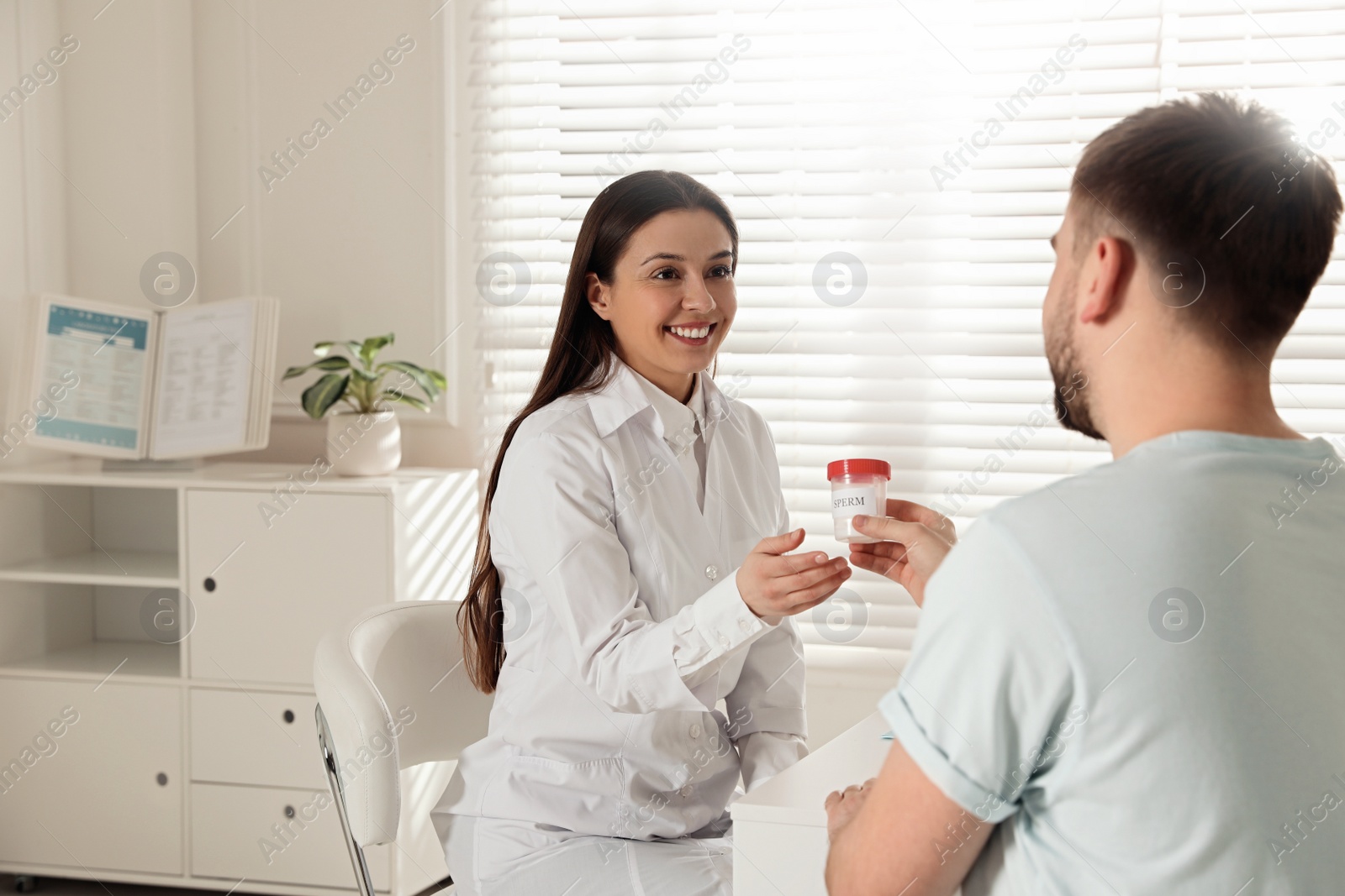 Photo of Donor giving container of sperm to doctor in hospital