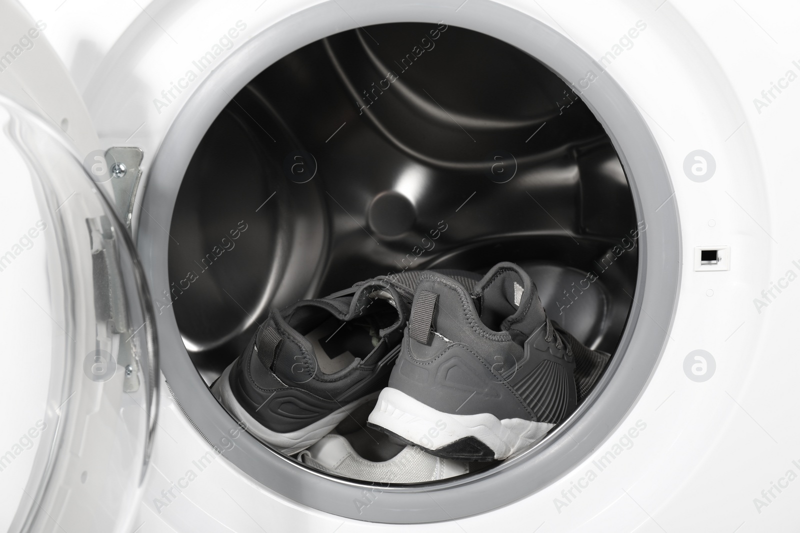 Photo of Stylish clean sneakers inside modern washing machine