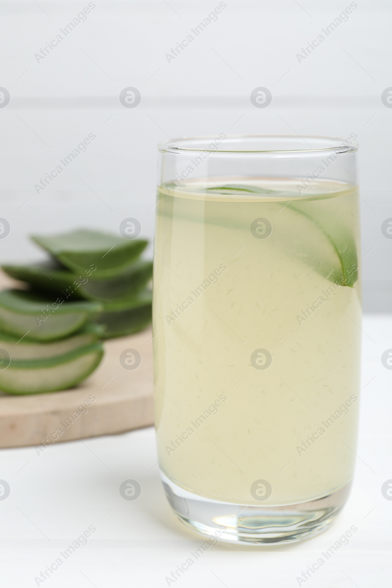 Photo of Tasty aloe juice in glass on white table, closeup