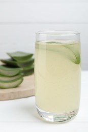 Photo of Tasty aloe juice in glass on white table, closeup