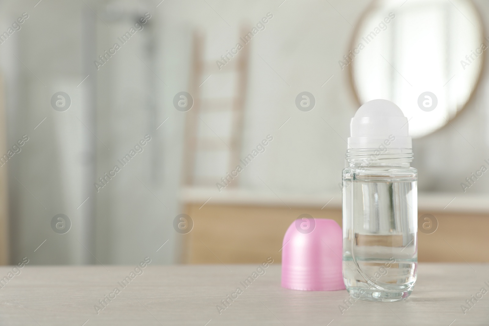 Photo of Open female roll-on deodorant on wooden table in bathroom. Space for text