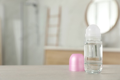 Photo of Open female roll-on deodorant on wooden table in bathroom. Space for text