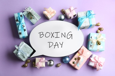 Photo of Speech bubble with phrase BOXING DAY and Christmas decorations on lilac background, flat lay