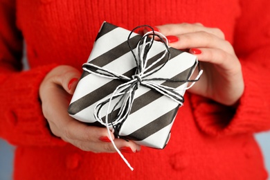 Young woman holding Christmas gift, closeup view