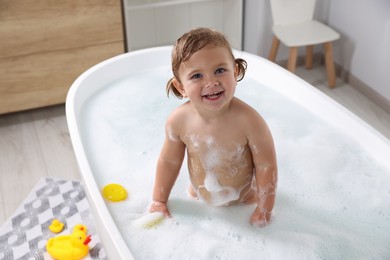 Happy little girl in foamy bath at home