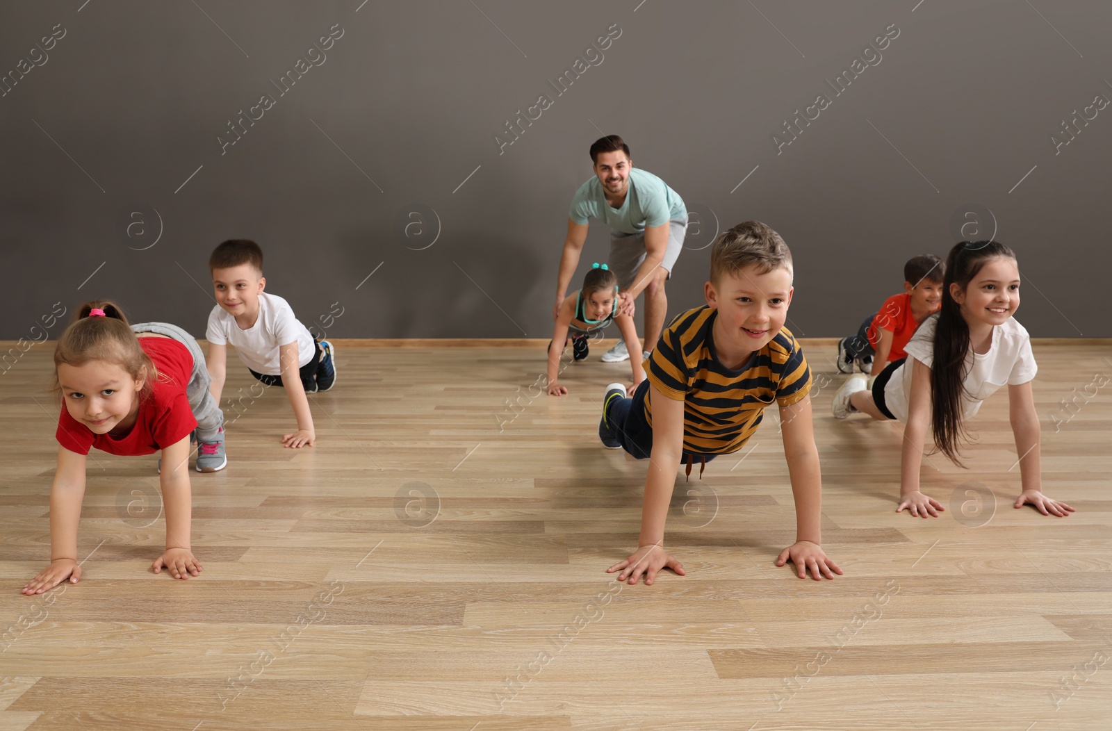 Photo of Cute little children and trainer doing physical exercise in school gym. Healthy lifestyle