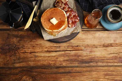 Photo of Delicious pancakes with maple syrup, butter and fried bacon on wooden table, flat lay. Space for text