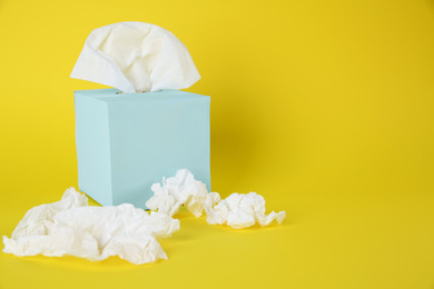 Photo of Used paper tissues and box on yellow background. Space for text