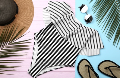 Flat lay composition with striped swimsuit and beach accessories on color background