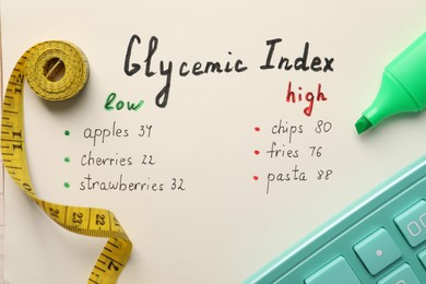 List with products of low and high glycemic index, marker, measuring tape and calculator, top view