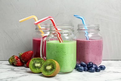 Mason jars with healthy detox smoothies and ingredients on table