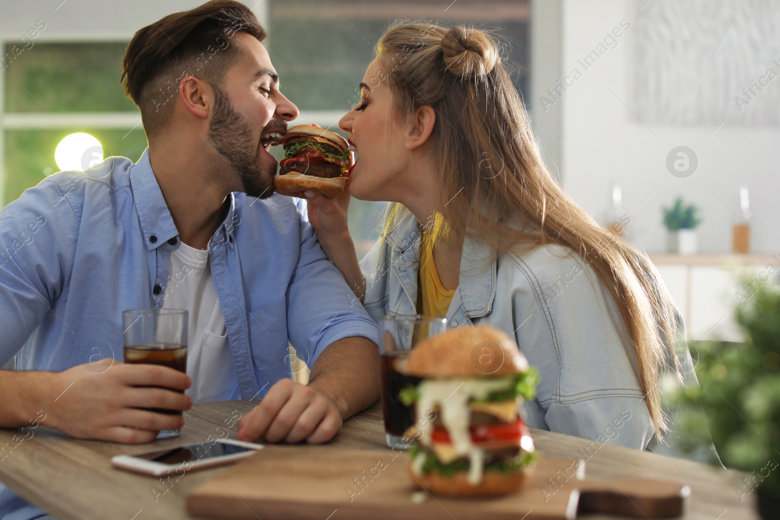 Photo of Happy young couple having lunch in burger restaurant