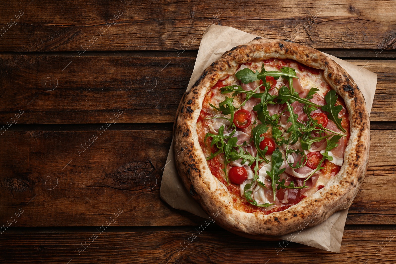 Photo of Tasty pizza with meat and arugula on wooden table, top view. Space for text