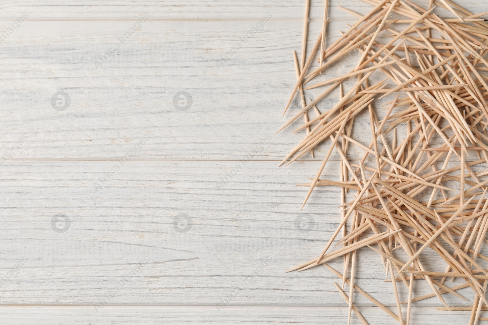 Photo of Disposable toothpicks on white wooden background, flat lay. Space for text