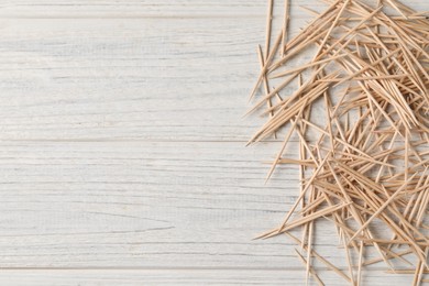 Photo of Disposable toothpicks on white wooden background, flat lay. Space for text