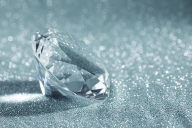Photo of Beautiful dazzling diamond on shiny glitter background, closeup. Space for text