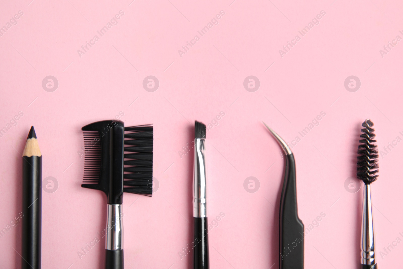 Photo of Set of professional eyebrow tools on pink background, flat lay