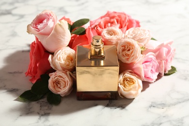 Photo of Bottle of perfume with beautiful roses on marble background