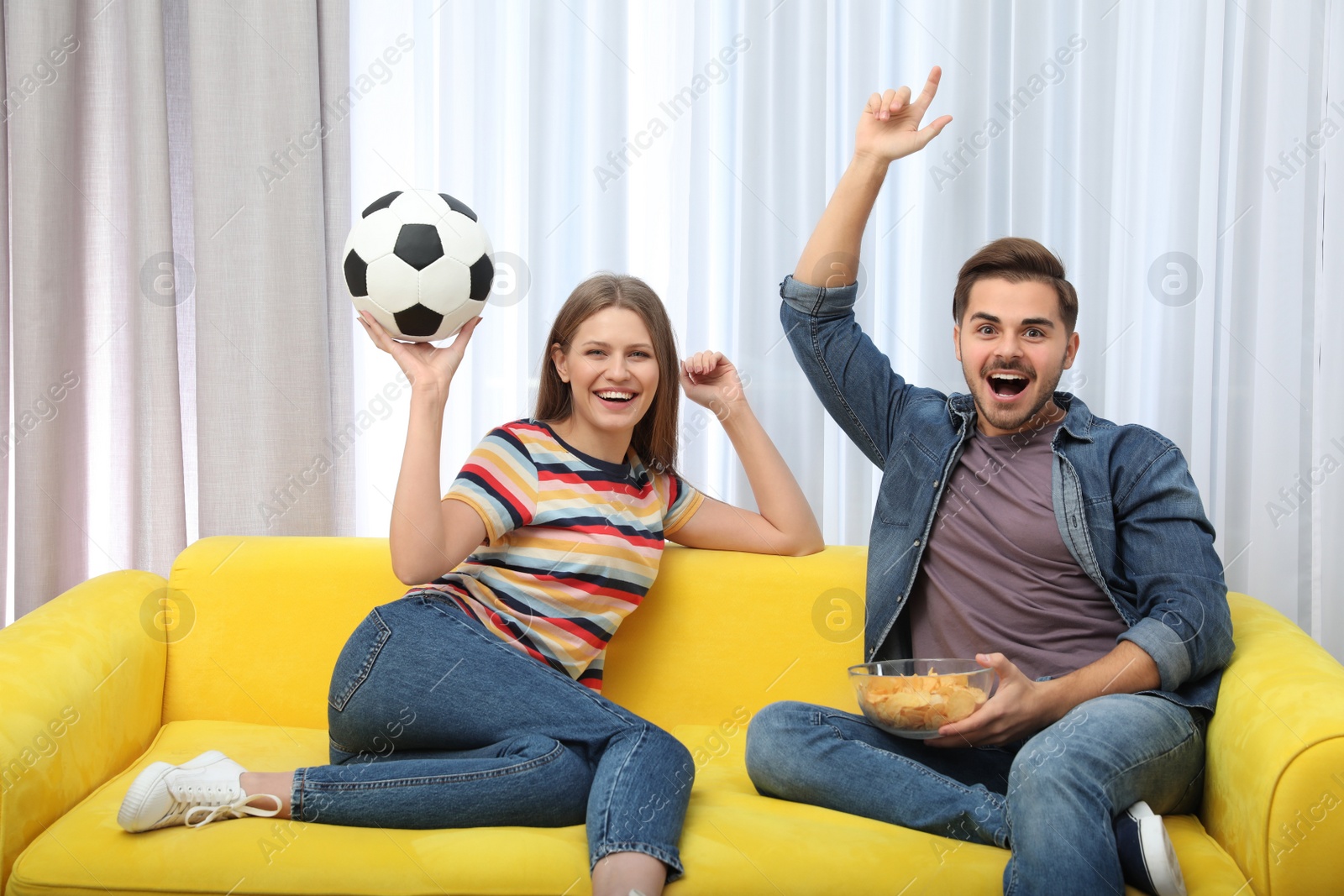 Photo of Couple watching soccer match on TV in living room