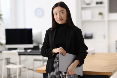 Portrait of beautiful businesswoman with laptop in office